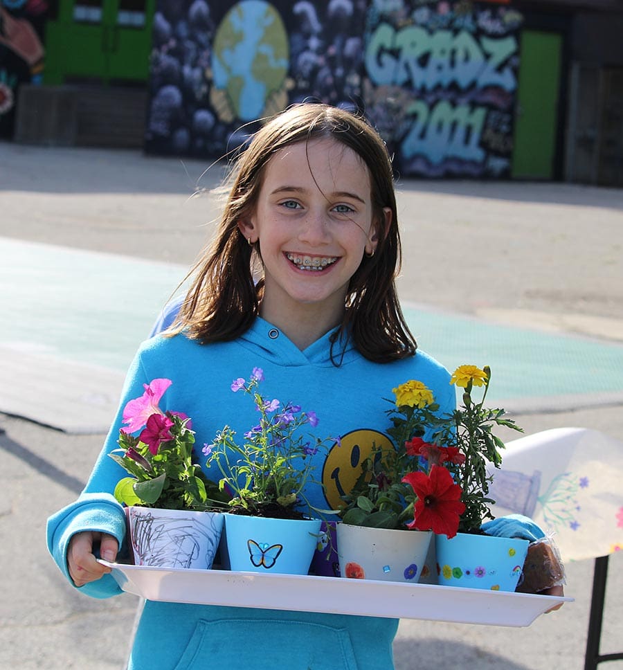 Two children in a classroom Student carrying a tray with flowers