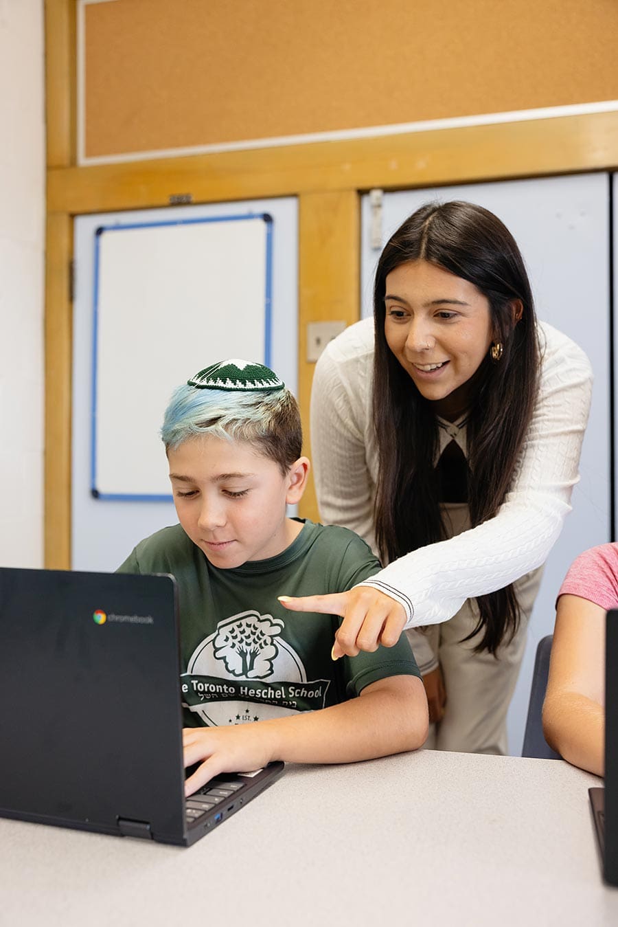 Child holding magnifyer Teacher with student on a computer